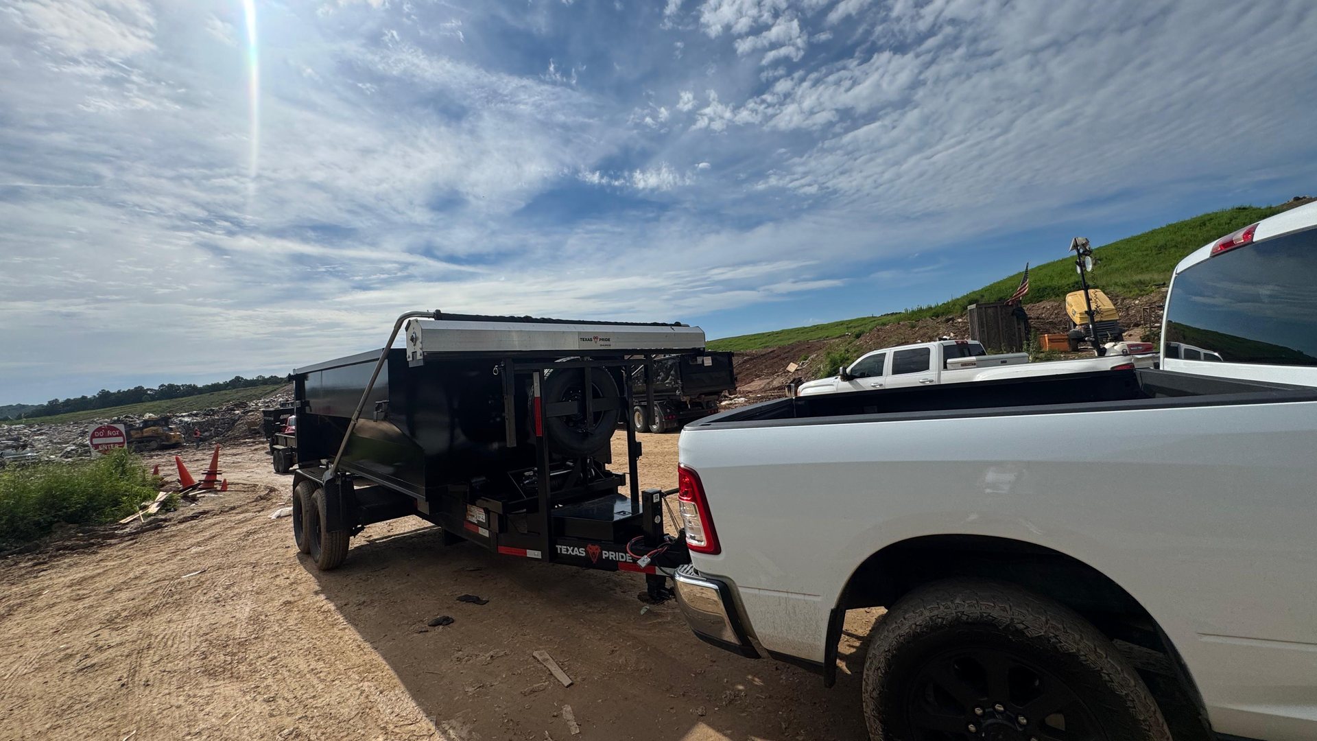 Black dumpster trailer staged at a construction job site under a wide sky